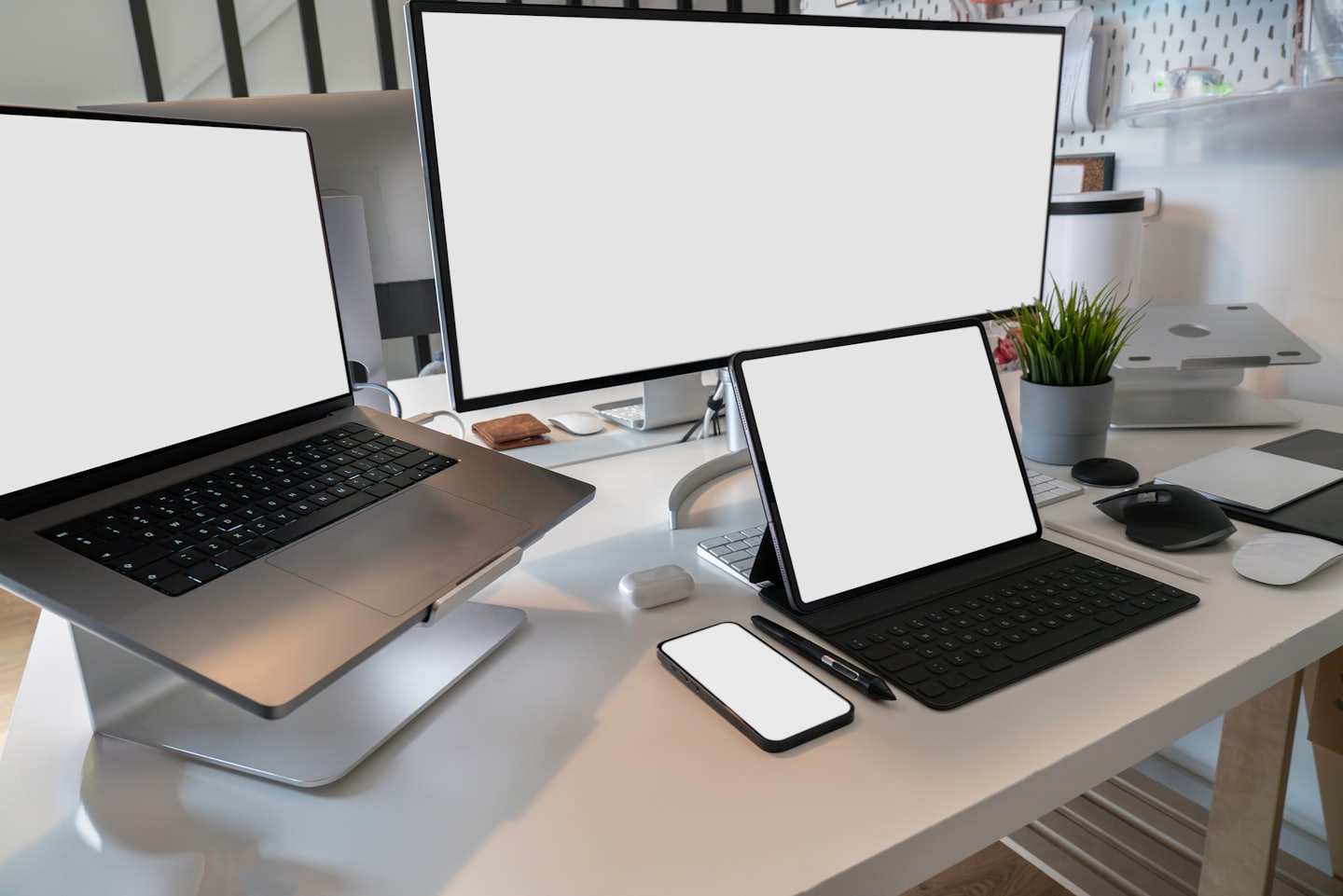 Organized desk with laptop, monitor, tablet, and smartphone.